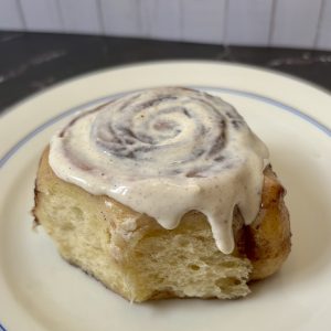 Sauerteig Zimtschnecken mit Frosting - frisch gebacken, fluffig und saftig auf einem Teller serviert