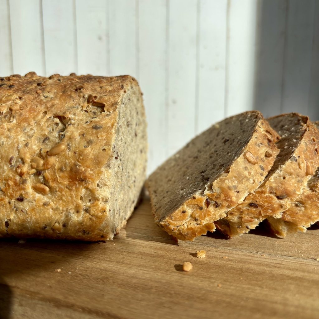 Sauerteig Mehrkorn Toastbrot. Fluffig und goldbraun gekacken. Aufgeschnitten auf einem Brett serviert.