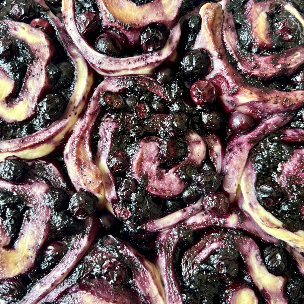 Nahaufnahme von Marmeladen-Schnecken mit Heidelbeeren, die über einer cremigen Füllung gewickelt sind.