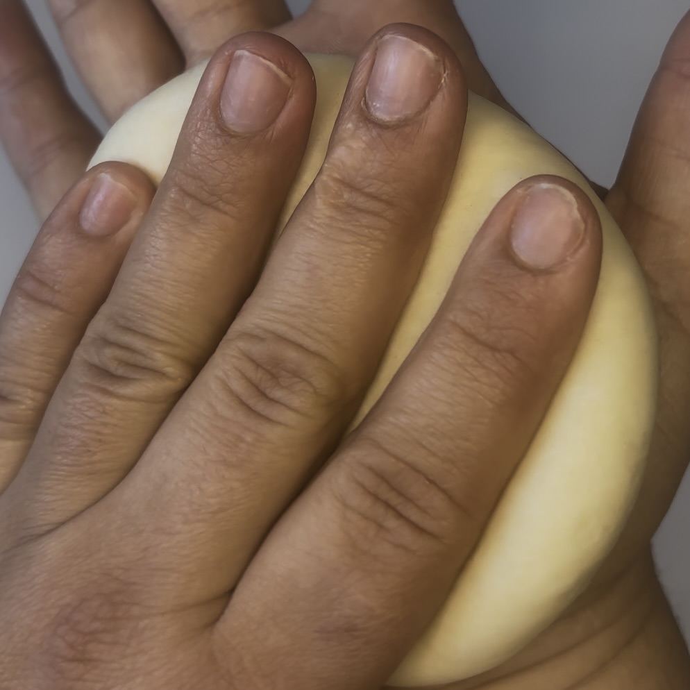 Sauerteig Burger Buns Teigkugel wird flachgedrückt.