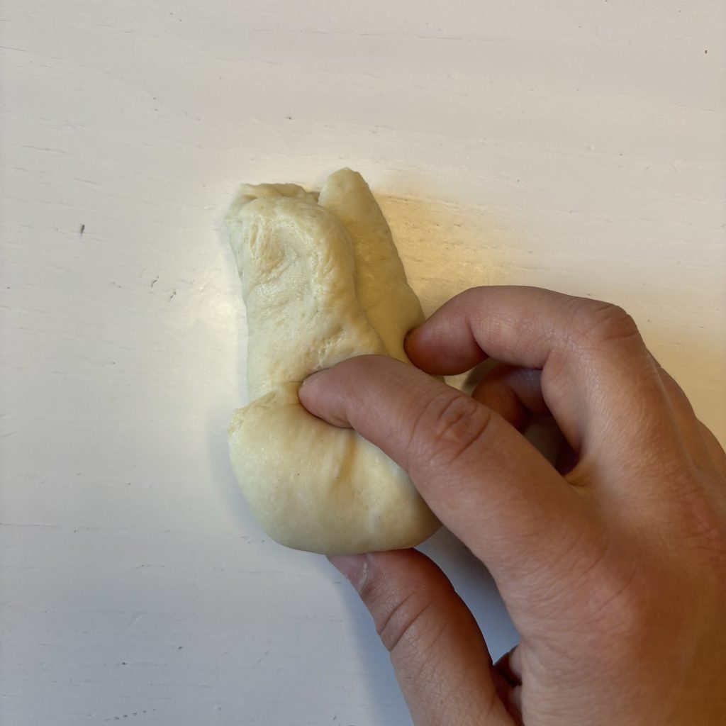 Sauerteig Burger Buns Teigstück flachgedrückt und geflatet und eingerollt.