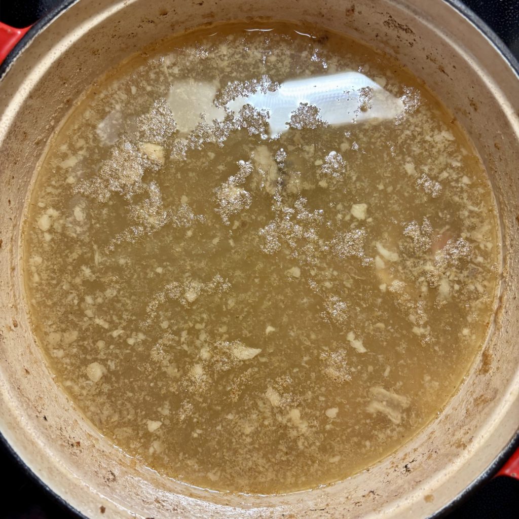 Rinder Knochenbrühe beim Kochen im Topf, leicht trüb durch Kollagen
