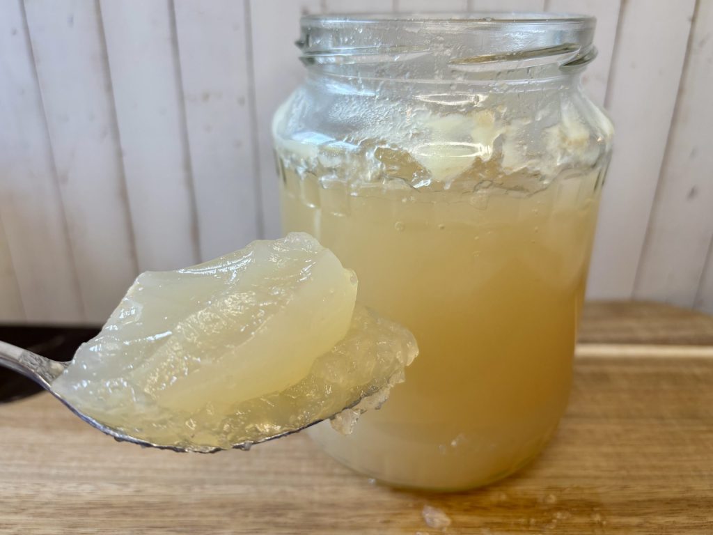 stark gelierte Knochenbrühe auf Löffel über dem Glas