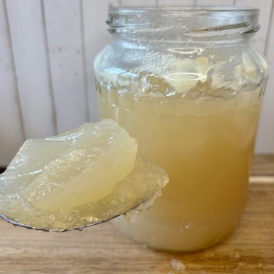 stark gelierte Knochenbrühe auf Löffel über dem Glas