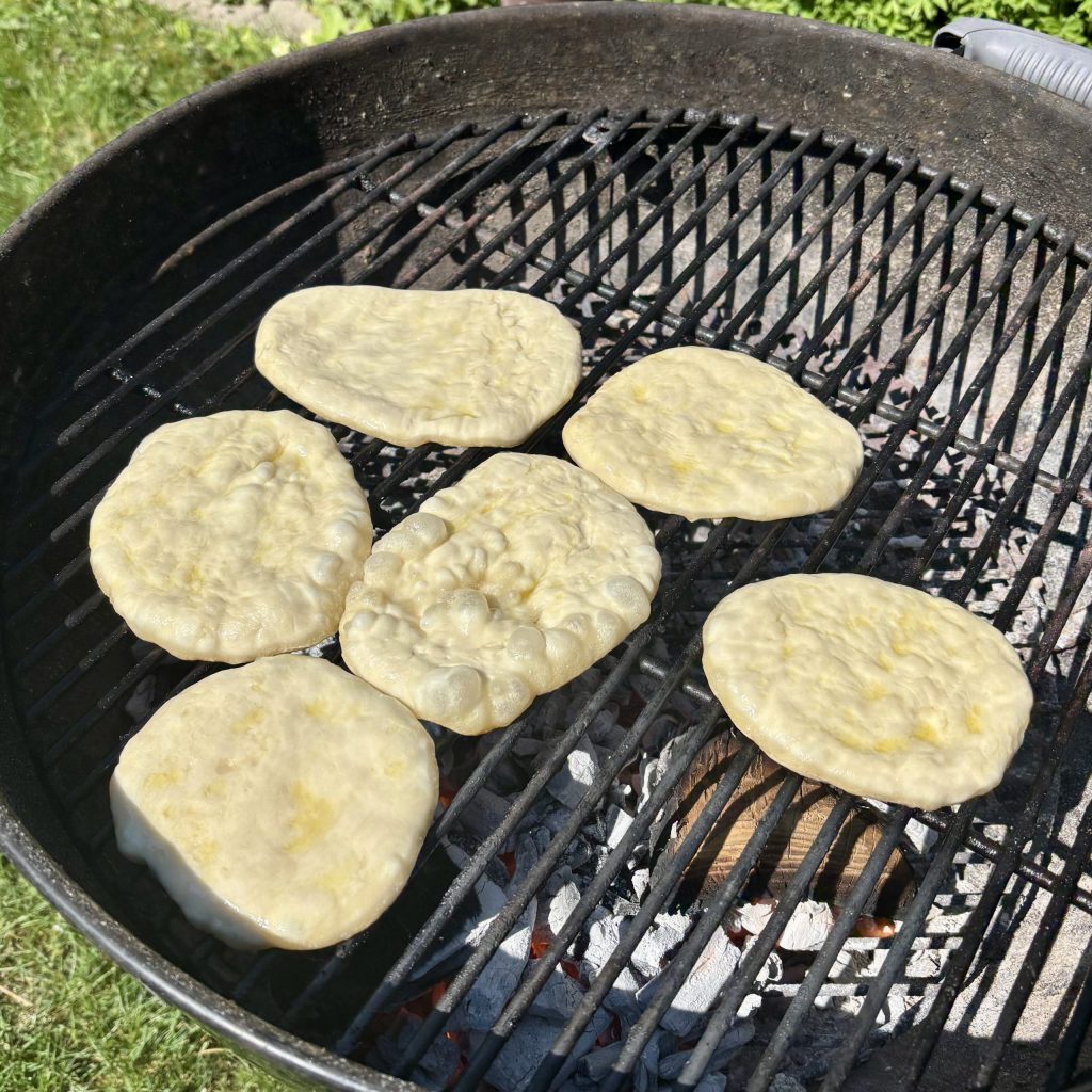 Rohes Grillbrot aus Sauerteig auf dem Grillrost vor dem Backen