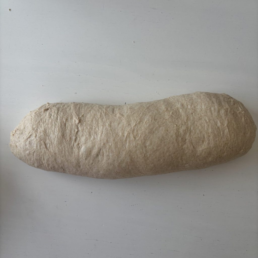 Länglich geformter Teig für Sauerteigbrot mit dunklem Mehl