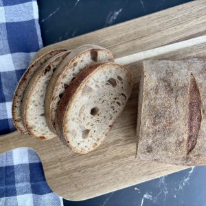 Sauerteigbrot mit dunklem Mehl in Scheiben auf Holzbrett