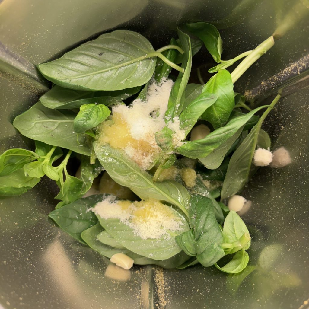 Frische Basilikumblätter, Knoblauch und Parmesan im Mixer für hausgemachtes Pesto