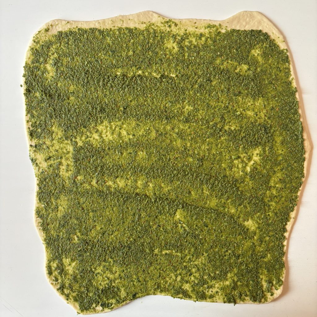 Ausgerollter Sauerteig mit grüner Basilikum-Pesto-Füllung