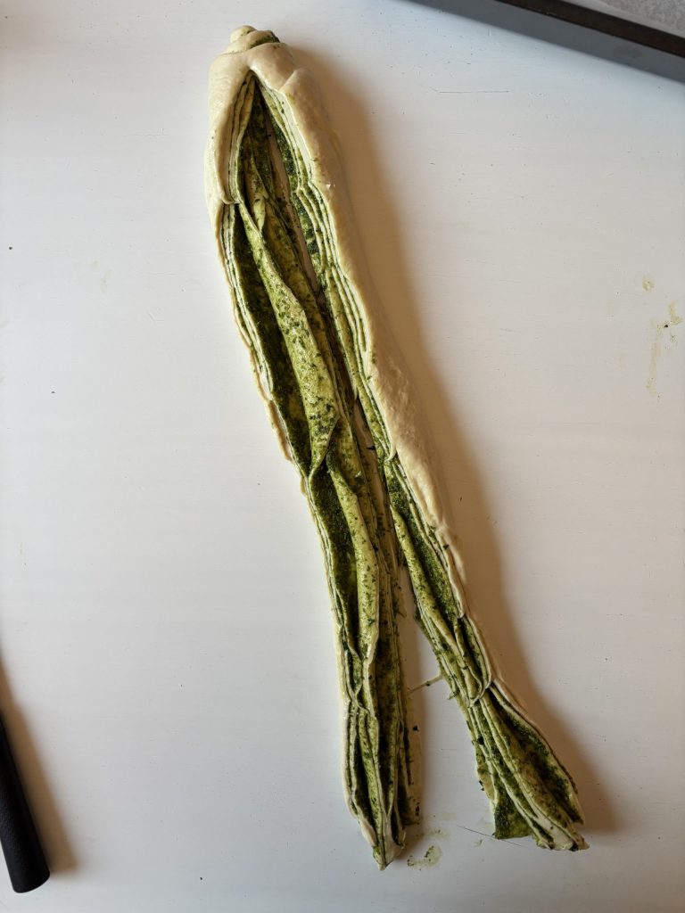 Langer Sauerteigstrang mit Pesto-Füllung beim Formen des Pestobrots