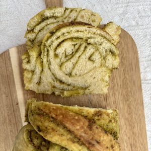 Aufgeschnittenes Sauerteig-Pestobrot mit grüner Pesto-Füllung auf einem Holzbrett