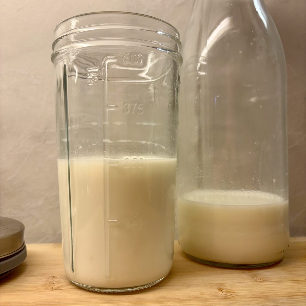 Milchkefir in einem Glas während der Fermentation, nebendran eine Flasche Milch