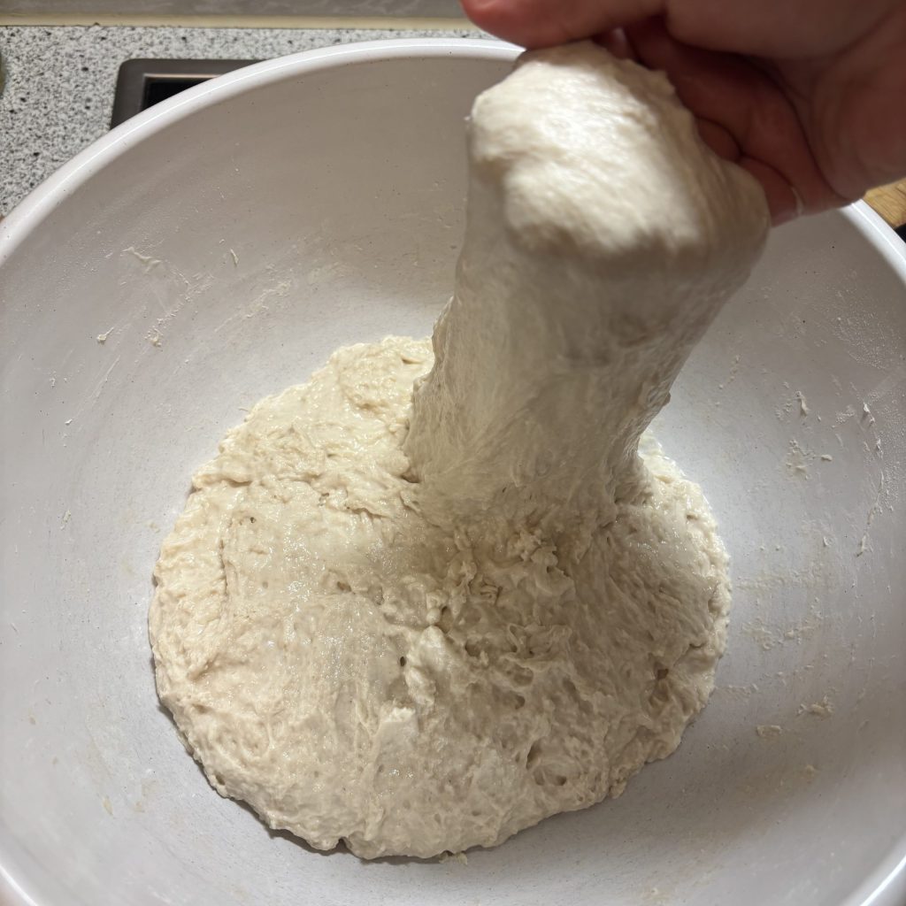 Sauerteig Ciabatta Teig wird in der Schüssel gedehnt und gefaltet