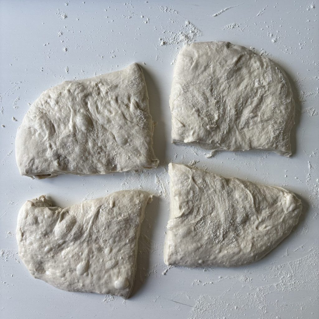 Vier ungebackene Sauerteig Ciabatta Brötchen auf bemehlter Arbeitsfläche
