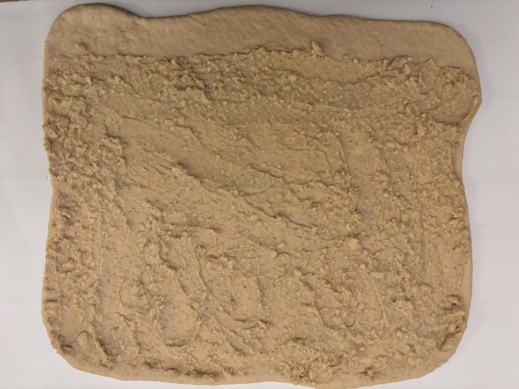 Sauerteigteig für Puddingschnecken mit Puddingfüllung gleichmässig bestrichen