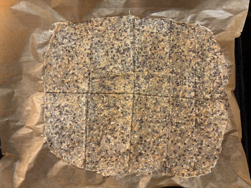 Sauerteig Knäckebrot mit Saaten auf Backpapier vor dem endgültigen Durchbacken