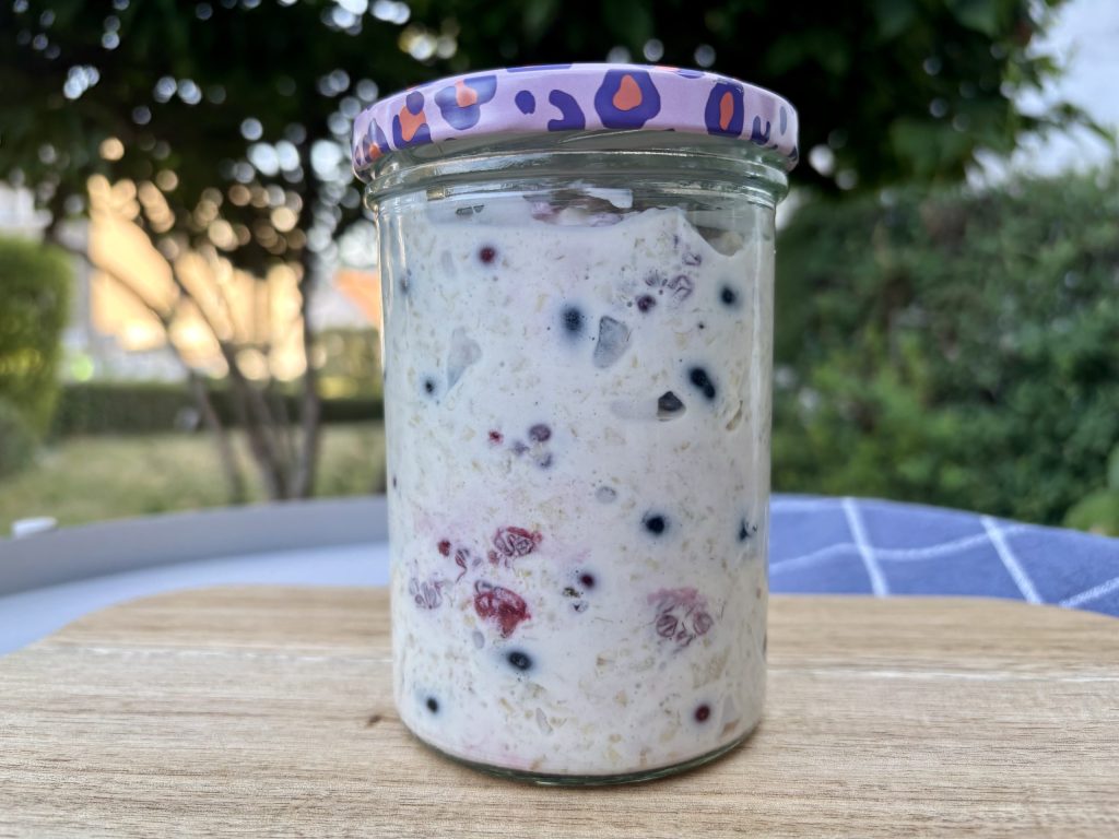 Birchermüesli mit Beeren im Glas auf einem Gartentisch