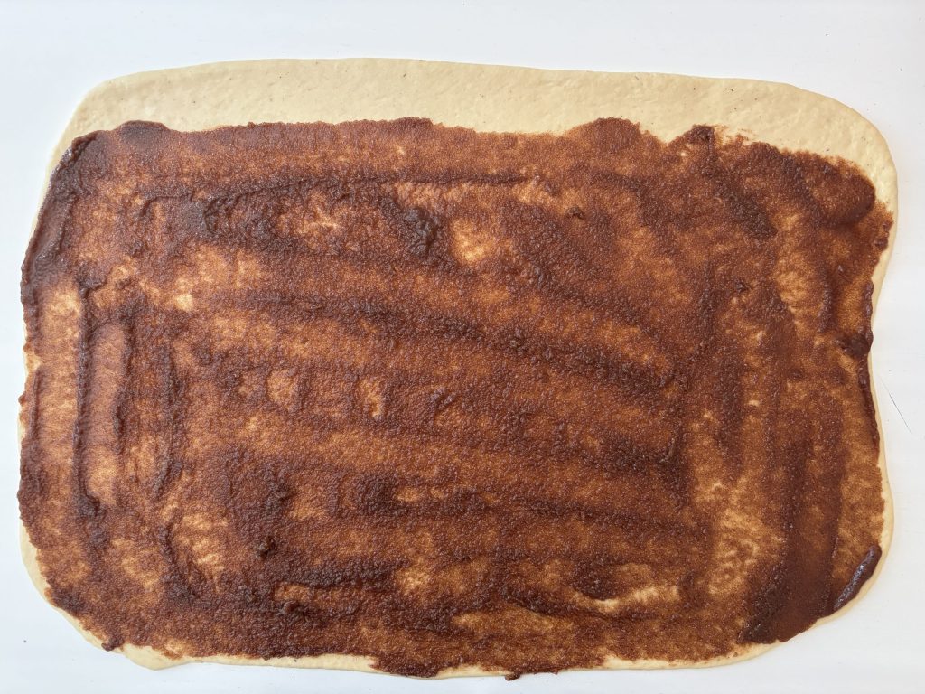 Ausgerollter Teig mit Zimtfüllung bestrichen