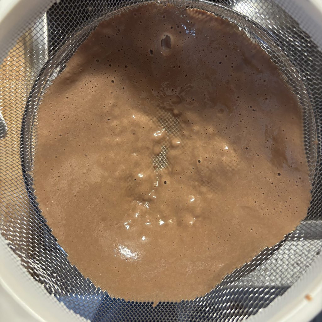 Schokoladencreme ohne Maizena wird durch ein Sieb gegeben