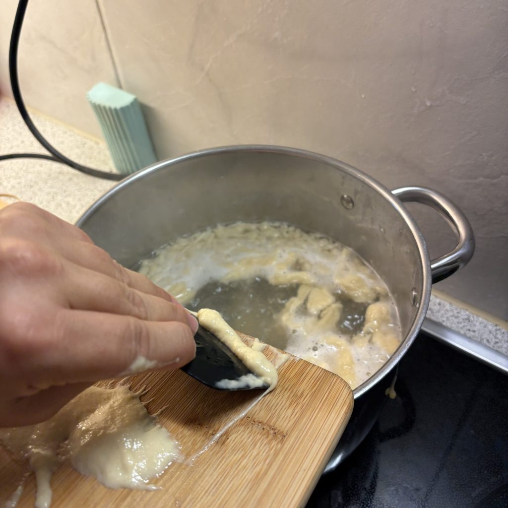 Sauerteig Spätzle vom Brett ins Wasser schaben
