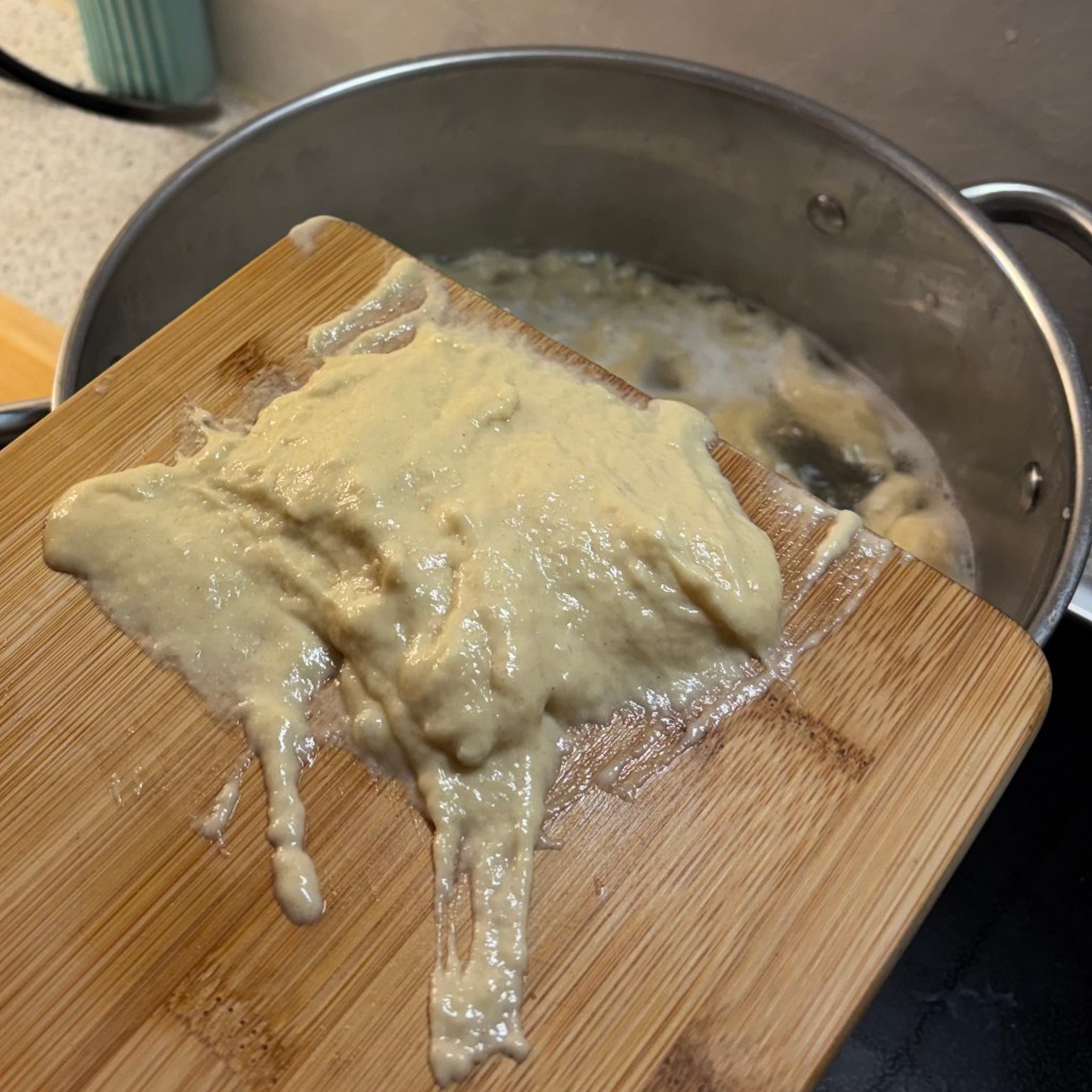 Spätzleteig mit Brett über kochendem Wasser