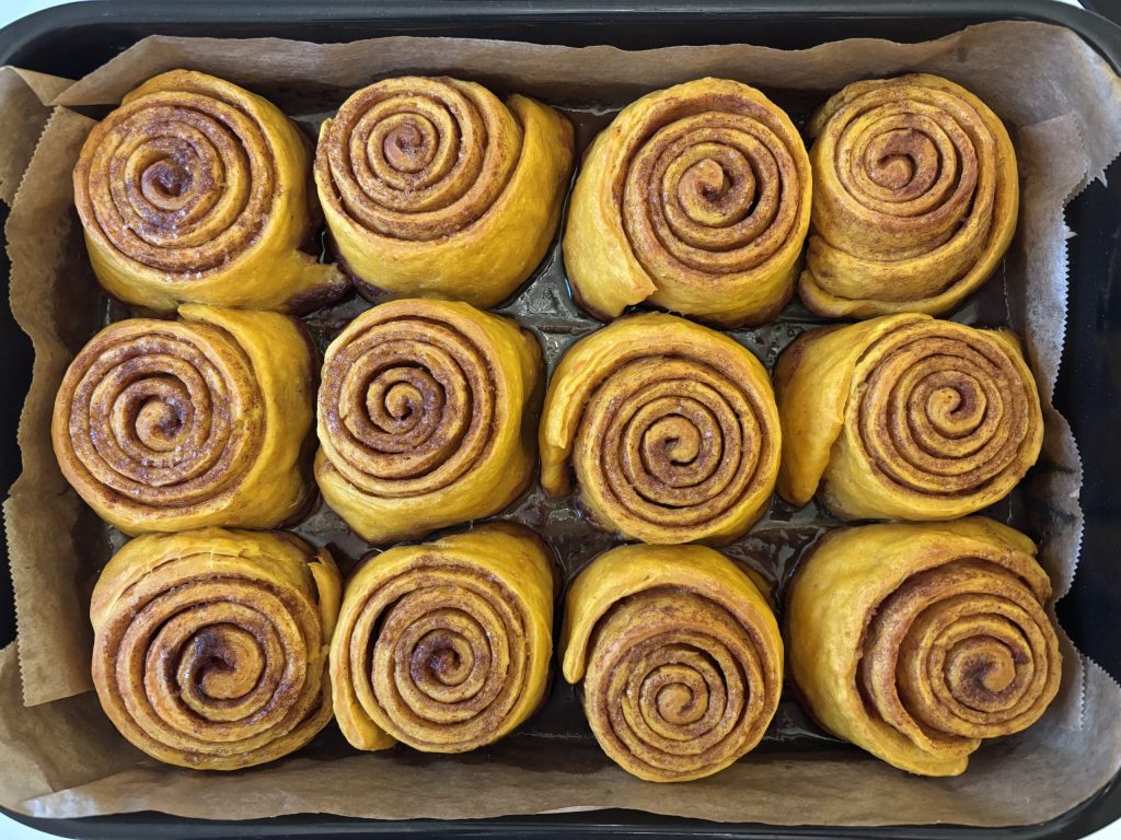 Frisch gebackene Sauerteig Kürbis Zimtschnecken mit Pumpkin Spice auf einem Backblech.