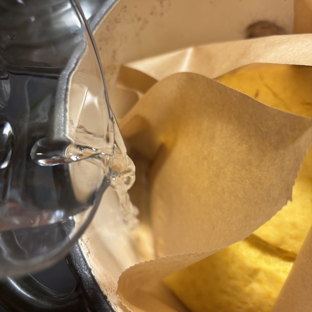 Wasser in den heissen Topf neben dem Kürbisbrot giessen