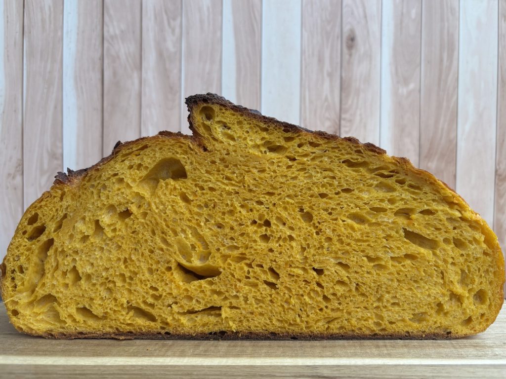 Angeschnittenes, oranges Sauerteig Kürbisbrot, mit luftiger Krume.