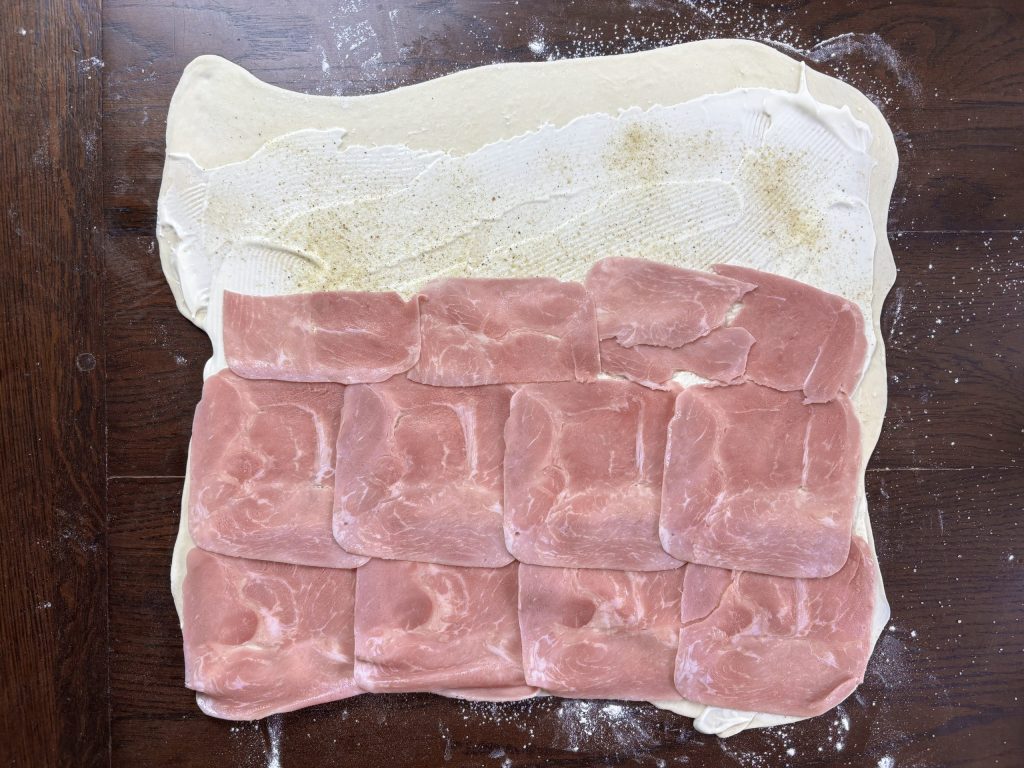 Ausgerollter Blätterteig mit Schinkenscheiben belegt